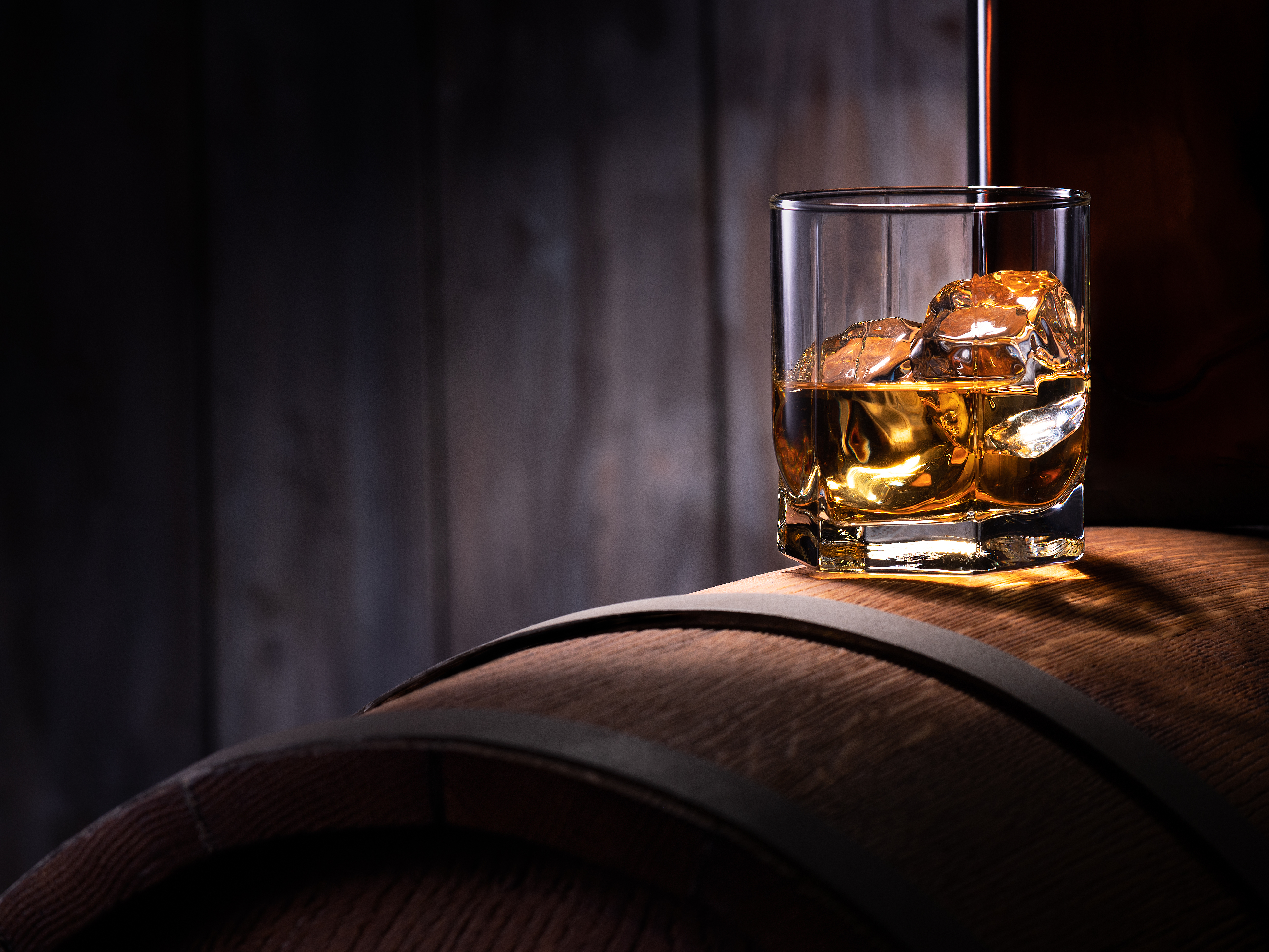 Glass,Of,Whiskey,With,Ice,Cubes,On,The,Wooden,Barrel