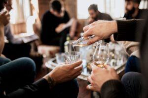 A group of people drinking Japanese whiskey from glasses, with a bottle pouring whiskey into a glass.